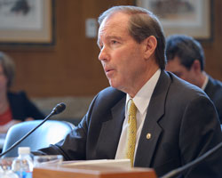 Tom Udall sidding at a desk with a microphone